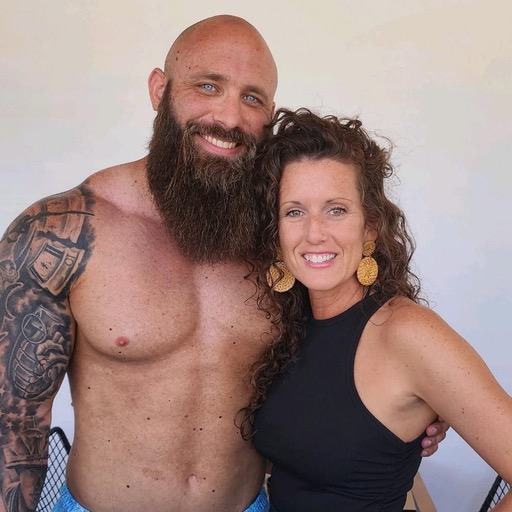 Okie Fit Fam — a tattooed bearded dad and an athletic curly-haired mom, both smiling.